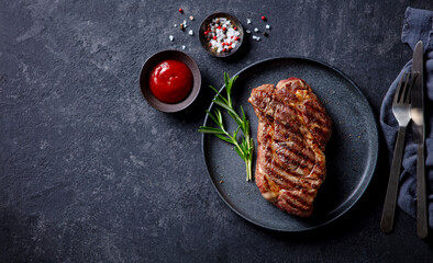 Beef Steak medium rare on a black plate. Dark background. Top view. Copy space.