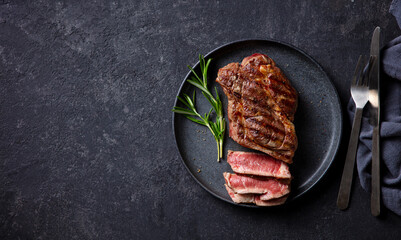 Beef Steak medium rare on a black plate. Dark background. Top view. Copy space.