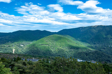 Fototapeta premium Landscape featuring lush green mountains against a peaceful cloudy blue sky, highlighting the beauty of nature