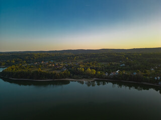 Panorama with a storage dam viewed from a drone in the countryside. A calm river that comes from the mountains among the green forests and flows into the lake at the edge of a village in Romania