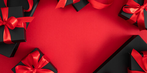 Black Friday Super Sale. Black gift box with red satin ribbon on red paper, frame, pattern. Top...