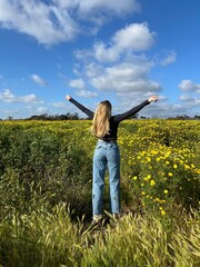 blonde woman in the flower field in jeans