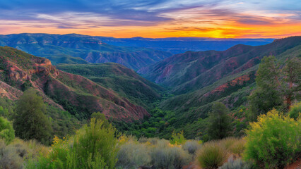 Fototapeta premium Stunning sunset view over a lush green valley surrounded by rugged mountains in summer