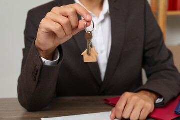 Real estate agent with house key at table, closeup