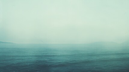Obraz premium A serene, tranquil view of an expansive ocean under a soft, misty atmosphere.
