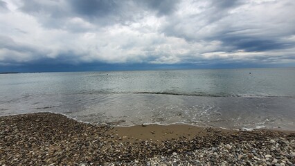 Sea, beach and pebbles, clouds in the sea.