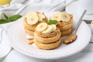 Tasty sandwiches with peanut butter, banana, mint and spoon on white wooden table, closeup