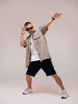 Full size body length young man wears grey shirt dancing lean back have fun spreading hands isolated on grey background studio
