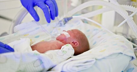 A dedicated healthcare professional provides gentle and compassionate care to a fragile newborn in the NICU environment. Nurse Caring For Newborn In Intensive Care Unit