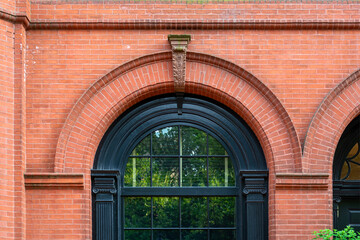 Red brick facade of a historic building with large arched window in Boston, Massachusetts, USA © Baharlou