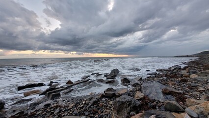 Sea, beach and pebbles, clouds in the sea.
