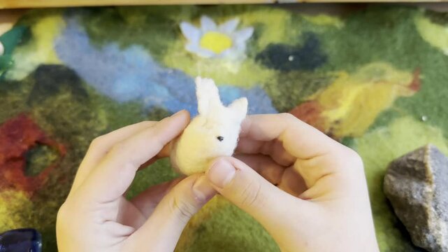 Close-up of Hands payinga Felted Wool Bunny Figurine, Crafting Handmade Animal Toys, Creative Art Process in Warm, Waldorf toys