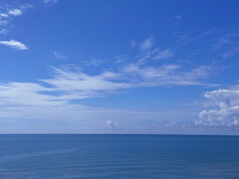 Calm sea blue water, blue sky, white clouds on horizon.