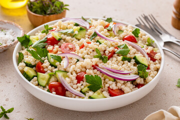 Pearl couscous salad with fresh vegetables and red onion