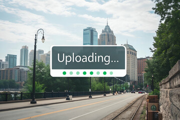A cityscape featuring skyscrapers and a road, with a digital "Uploading..." indicator overlaying the scene.