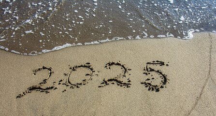 tropical New Year 2025 written in sand on the beach
