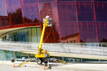 Glass facade cleaning works of a modern building using a modern telescopic boom lift with a basket