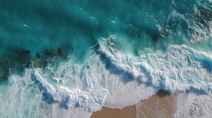 Fototapeta premium Ocean Waves Crashing on Sandy Beach: Aerial view of turquoise ocean waves breaking on a sandy beach. Perfect for travel, vacation, or nature-themed projects.
