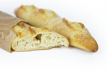 Two freshly baked baguettes, one wrapped in brown paper bag, Artisan French baguettes with crispy crusts in paper packaging. Isolated on a white background. Closeup. Clipping path. Copy space