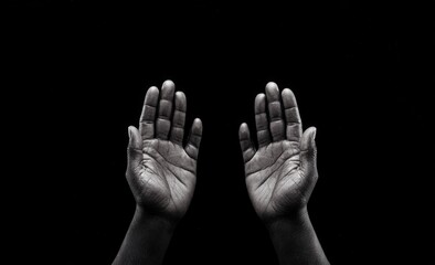 Hands reaching upwards in a gesture of prayer or supplication against a dark background