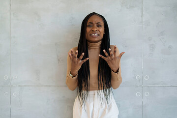 Worried African American businesswoman gestures , wearing formal attire, standing against the...