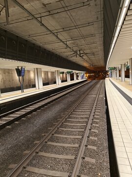 An empty train platform in Sweden at night with parallel tracks extending into the distance. The underground setting and artificial lighting give it a calm, urban feel