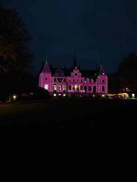 An illuminated historic building at night, bathed in purple light, creating a striking and majestic appearance against the dark sky.