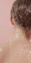 Fototapeta premium Water droplets glisten on the back of a woman's neck as she enjoys a refreshing skincare moment, illuminated by soft lighting against a pastel backdrop