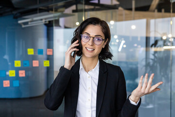 Young business woman talking on phone in contemporary office. Professional communication and...