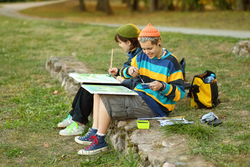 two young and innovative female artists conducting an outdoor painting lesson. Surrounded by...