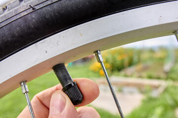Cap of bicycle tire is removed by cyclist fingers before inflating tube with air.
