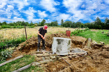 When installing septic tank, worker pushes concrete rings one over other.