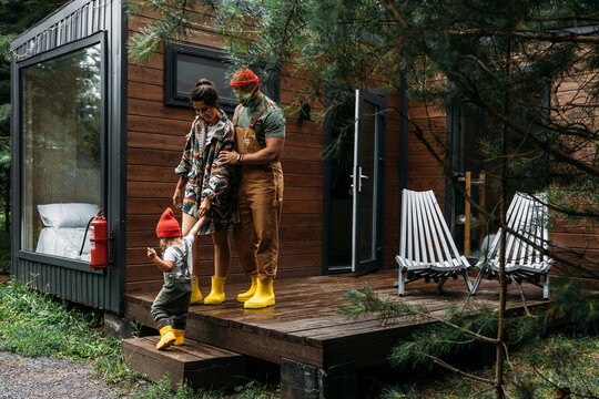 A happy family on the background of a country house. A stylish family on the background of a forest house. Vacation in the country. The family is resting at the cottage. A stylish family