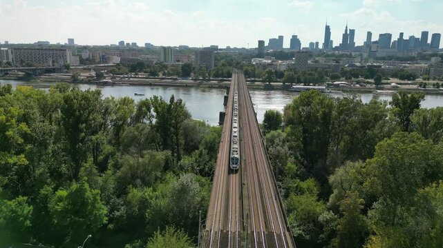 Train passing bridge in the city during day in summer