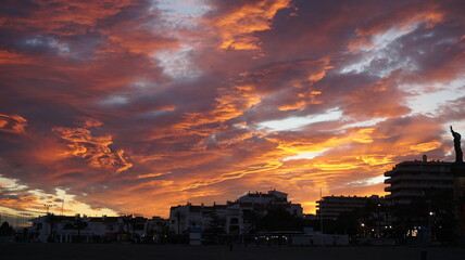 Fiery Sunset Over Coastal City Silhouette with Dramatic Clouds