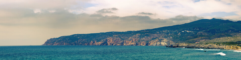 Stunning panorama view of guincho beach cliffs meeting the turquoise atlantic ocean near cascais, portugal
