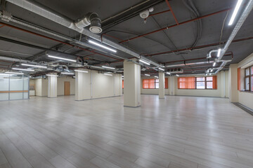 An open space in a modern office building. Beige floor tiles, red blinds on the windows. .Without furniture and equipment.
