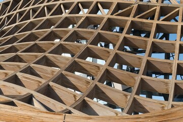 Abstract curved wooden framed sections of decorative wall or shade roof. Hardwood timber grid slats pattern facade finishing. Modern eco urban architecture as background. 