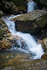 Fototapeta premium A close-up view of a small waterfall flowing over moss-covered.