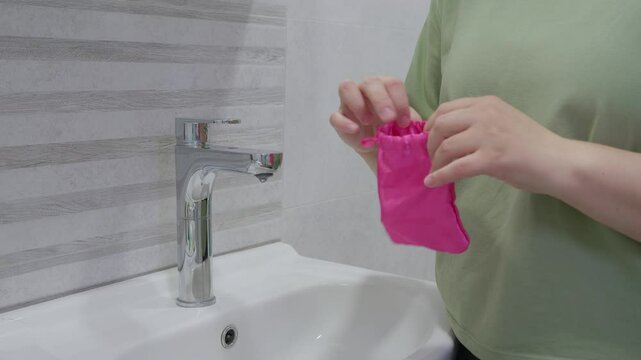 woman open fabric bag with silicone menstrual cup at bathroom. Alternative ecological feminine hygiene product. menstruation waste-free concept