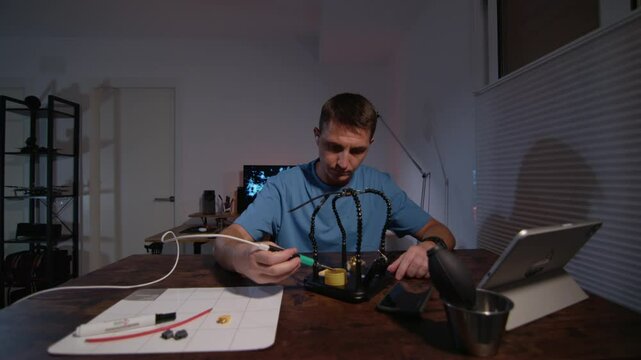 A man is Soldering power connectors in a DIY electronics project in the comfort of his home workshop