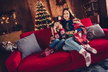 Obraz premium Full size photo of two peaceful people mother daughter sit couch cookies cover eyes new year xmas apartment indoors