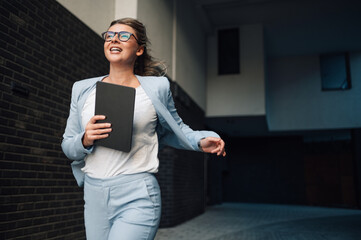Smiling businesswoman running holding tablet in hand