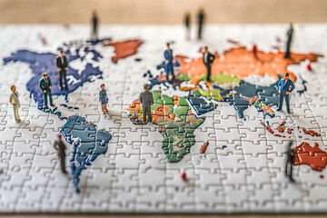 Naklejka premium Miniature Figures Standing on a World Map Puzzle