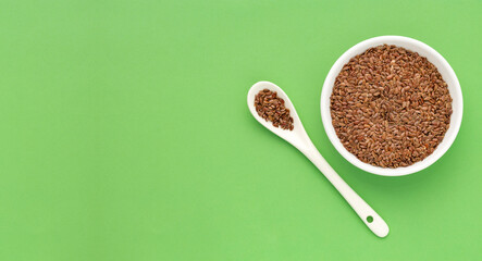 Organic dried flax seeds in bowl and spoon - Linum usitatissimum.