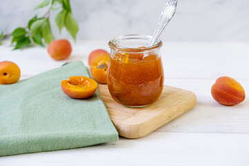 Homemade apricot jam in glass jar on kitchen white background. Summer harvest and canned food. 