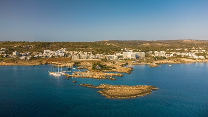 Aerial view of coastal town with clear waters and rocky shores.