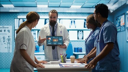 Skilled team of medics examine x ray scans and discuss health care plans during a research meeting....