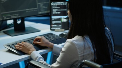 Person with paraplegia working in inclusive server hub workspace, typing on PC. Woman in wheelchair...