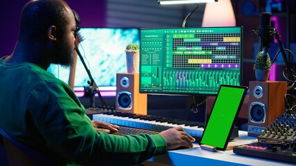 Songwriter composer mixing and mastering tracks next to green screen, operating on digital audio pc...
